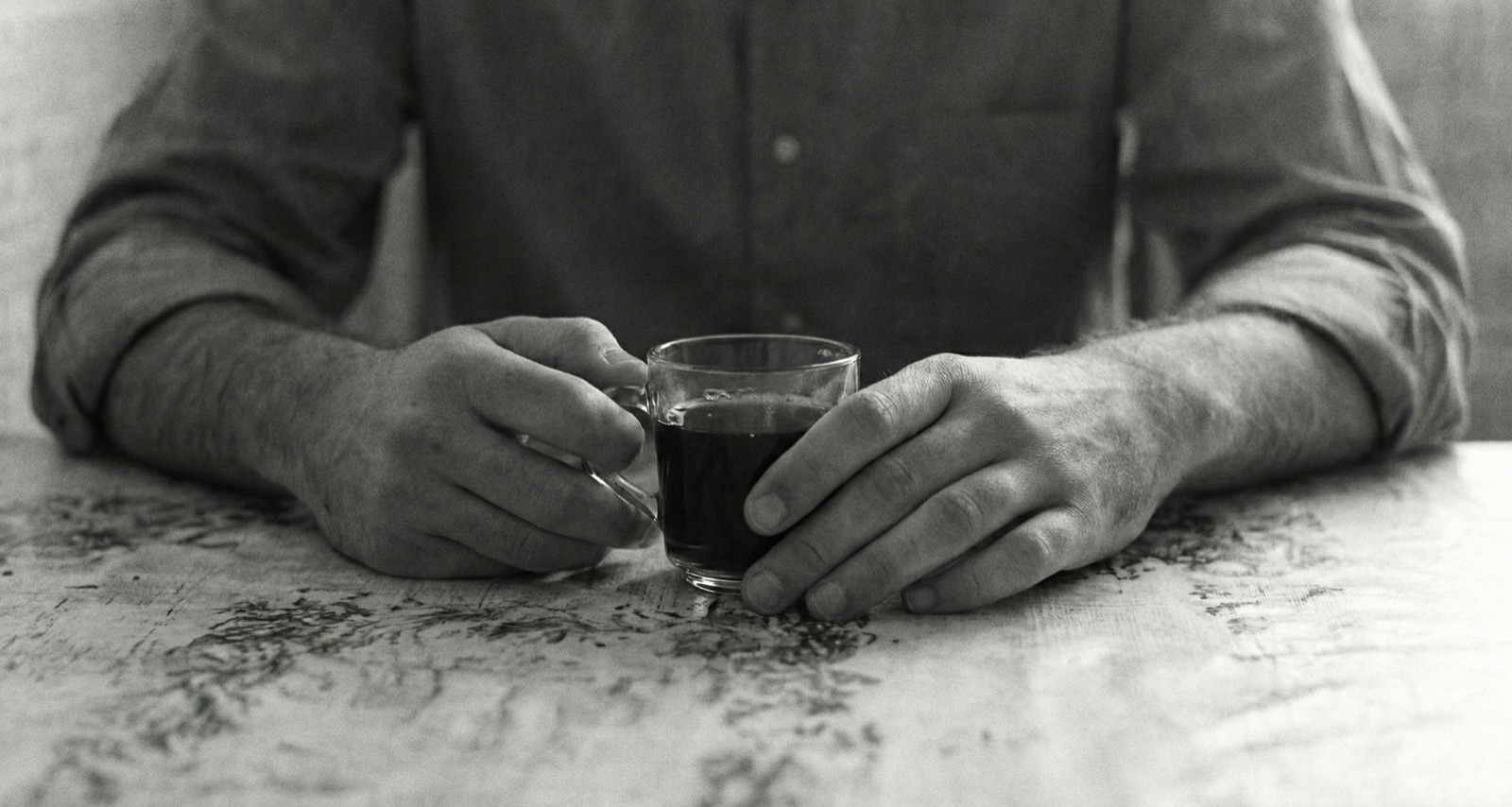 Michael's rough hands around a small glass of black coffee