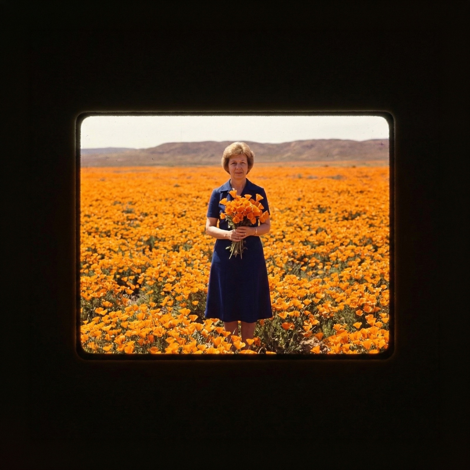 Miryam in a poppy field holding a bouquet
