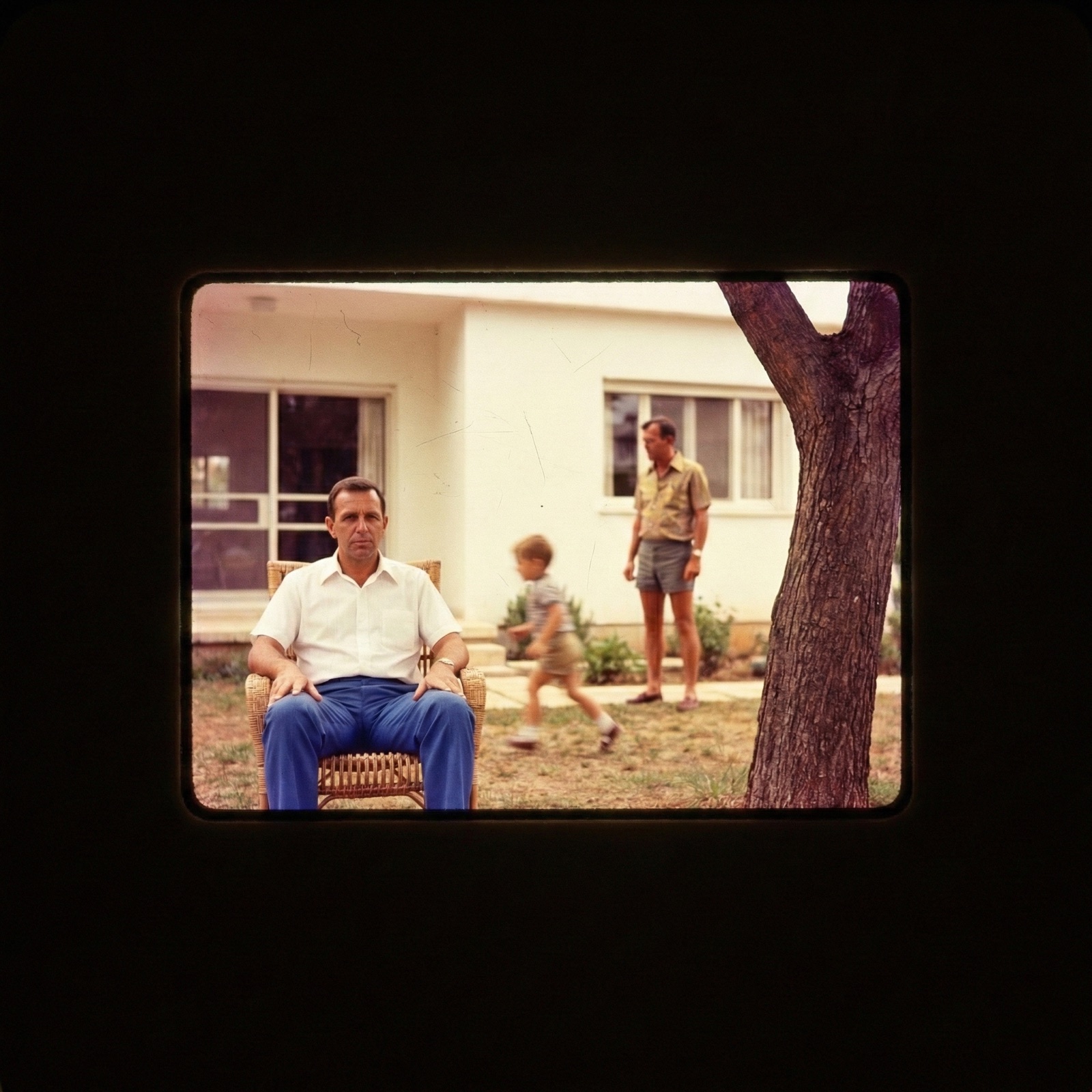 Yoram seated in the yard, Eyal and a child behind him